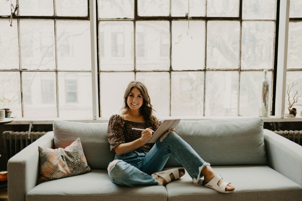 alane gianetti of write pretty for me sitting on a couch with a notepad and discussing how to boost referrals from past clients and wedding pros