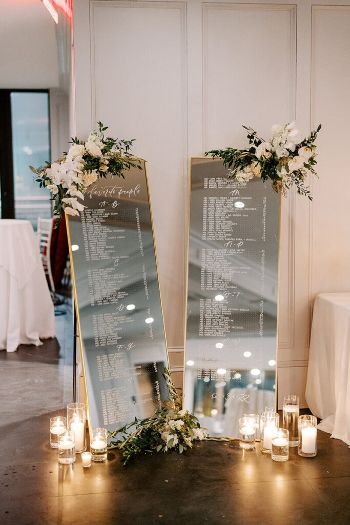 Elegant mirrored wedding seating charts with calligraphy, floral accents, and candles — perfect visual content for marketing tips for calligraphers.
