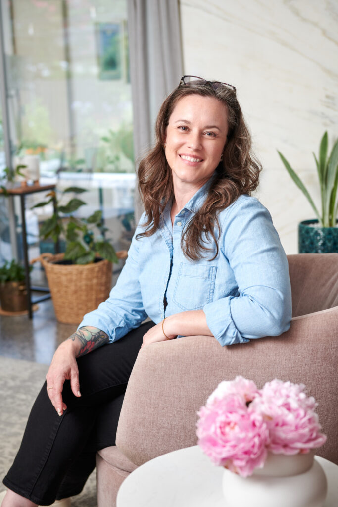 Meredith Stroud relaxing in a lounge chair at home surrounded by plants and pink peonies