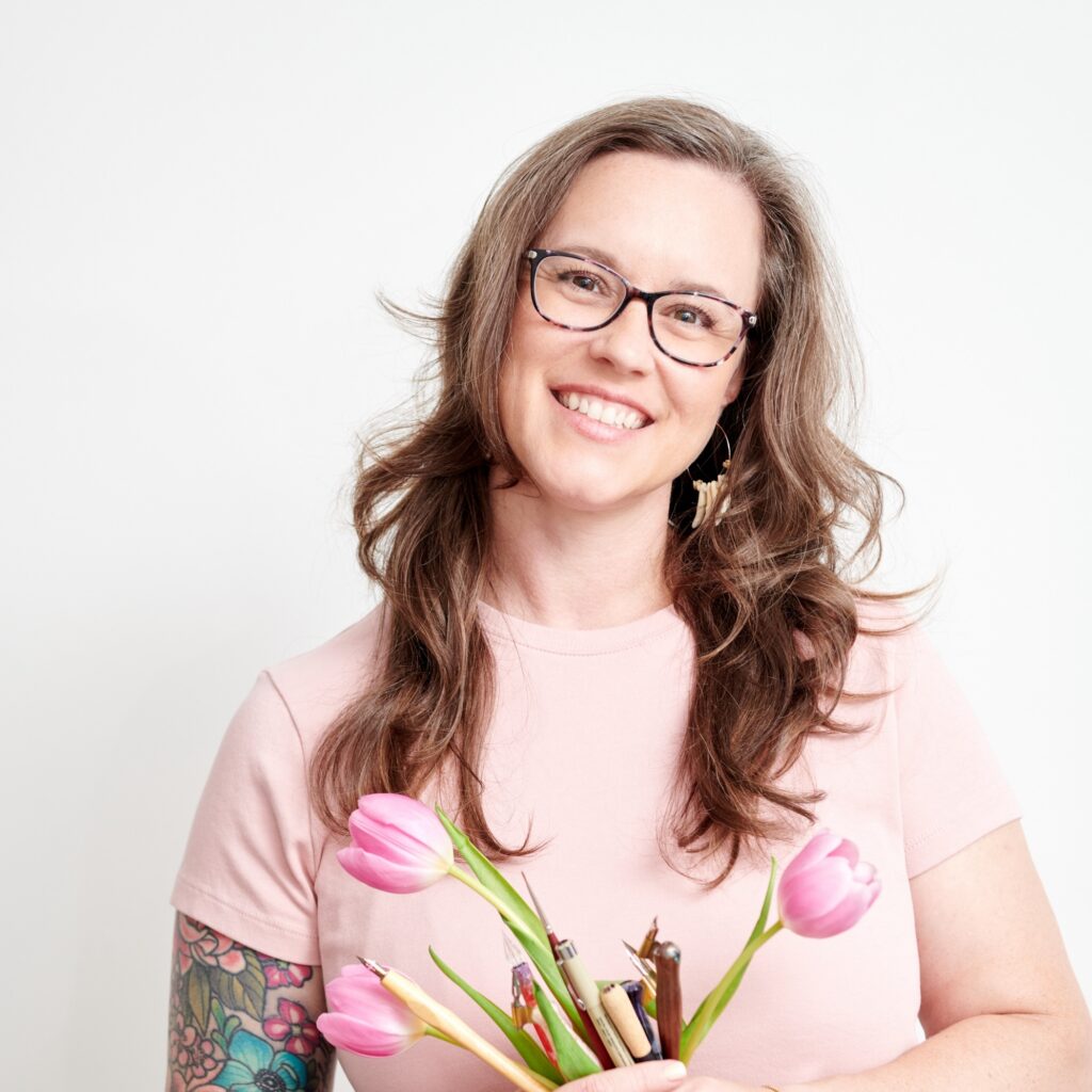 Meredith Stroud smiling and holding a bouquet of pink tulips and calligraphy pens